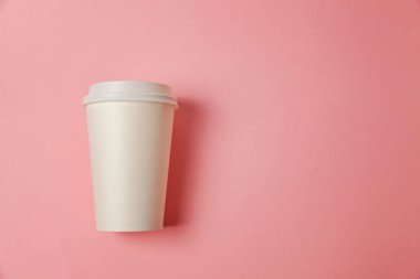 Sade bir şekilde yatıyordu tasarım kağıt kahve Kupası pembe pastel renkli şık arka plan üzerinde düz. Paket servisi olan restoran içki kabı. Günaydın uyanık kavramı uyandır. İçki mockup şablonu. Üstten görünüm kopya alanı