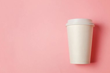 Sade bir şekilde yatıyordu tasarım kağıt kahve Kupası pembe pastel renkli şık arka plan üzerinde düz. Paket servisi olan restoran içki kabı. Günaydın uyanık kavramı uyandır. İçki mockup şablonu. Üstten görünüm kopya alanı