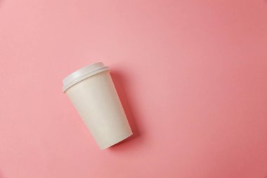 Sade bir şekilde yatıyordu tasarım kağıt kahve Kupası pembe pastel renkli şık arka plan üzerinde düz. Paket servisi olan restoran içki kabı. Günaydın uyanık kavramı uyandır. İçki mockup şablonu. Üstten görünüm kopya alanı