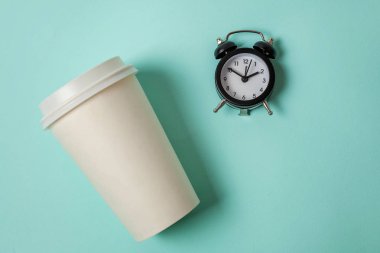 Sadece düz yatıyordu tasarım kağıt kahve Kupası ve pastel renkli şık arka plan mavi çalar saat. Paket servisi olan restoran içki ve kahvaltı içecek. Günaydın uyanık kavramı uyandır. Üstten görünüm kopya alanı