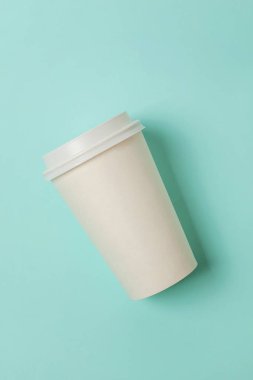 Sade bir şekilde yatıyordu tasarım kağıt kahve Kupası mavi pastel renkli şık arka plan üzerinde düz. Paket servisi olan restoran içki kabı. Günaydın uyanık kavramı uyandır. İçki mockup şablonu. Üstten görünüm kopya alanı