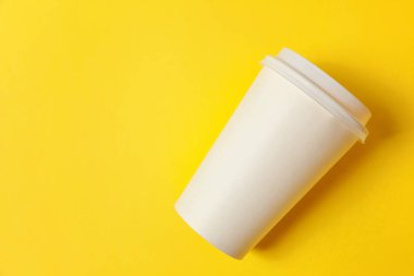 Sade bir şekilde yatıyordu tasarım kağıt kahve Kupası sarı renkli şık arka plan üzerinde düz. Paket servisi olan restoran içki kabı. Günaydın uyanık kavramı uyandır. İçki mockup şablonu. Üstten görünüm kopya alanı
