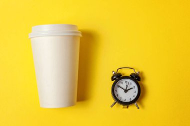 Sadece düz yatıyordu tasarım kağıt kahve Kupası ve sarı renkli şık arka planda çalar saat. Paket servisi olan restoran içki ve kahvaltı içecek. Günaydın uyanık kavramı uyandır. Üstten görünüm kopya alanı