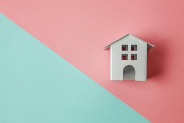 Sadece tasarım mavi, pembe pastel renkli trendy geometrik arka plan izole bir minyatür beyaz oyuncak ev. Mortgage Emlak sigorta rüya ev concept. Düz yatıyordu üstten görünüm kopya alanı