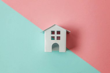 Sadece tasarım mavi, pembe pastel renkli trendy geometrik arka plan izole bir minyatür beyaz oyuncak ev. Mortgage Emlak sigorta rüya ev concept. Düz yatıyordu üstten görünüm kopya alanı