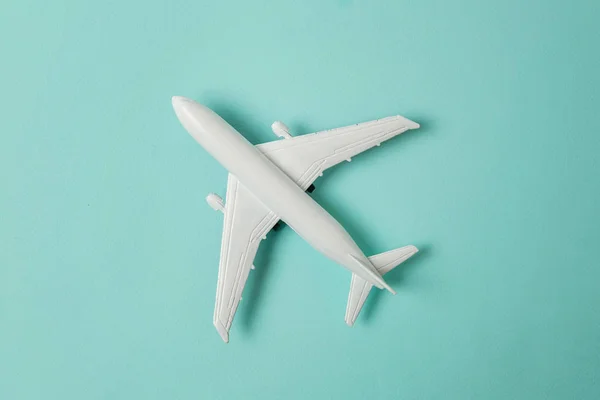 Simply flat lay design miniature toy model plane on blue pastel colorful paper trendy background. Travel by plane vacation summer weekend sea adventure trip journey ticket tour concept