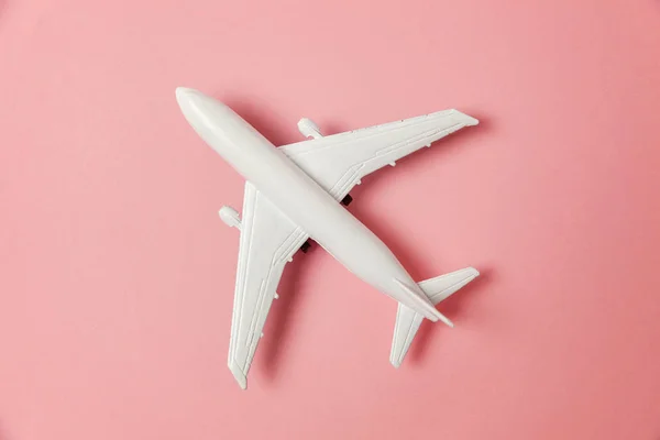 简单平坦的平面设计微型玩具模型平面上的粉红色柔和的彩色纸新潮的背景 乘坐飞机度假暑假海险旅行旅游票务旅游概念 — 图库照片