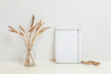 Dikey çerçeve mockup vahşi çavdar kokulu beyaz duvarının yakınında cam vazoda. Boş çerçeve tanıtım tasarım için sahte. Modern sanat için şablon çerçeveleme. Hygge İskandinav tarzı doğal Eko ev dekorasyonu