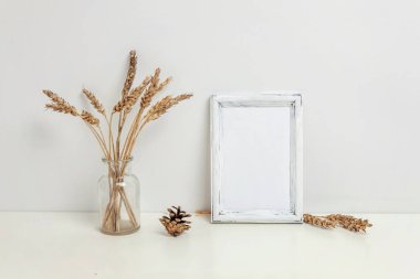 Dikey çerçeve mockup vahşi çavdar kokulu beyaz duvarının yakınında cam vazoda. Boş çerçeve tanıtım tasarım için sahte. Modern sanat için şablon çerçeveleme. Hygge İskandinav tarzı doğal Eko ev dekorasyonu
