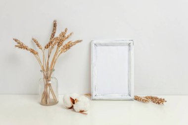 Dikey çerçeve mockup vahşi çavdar kokulu beyaz duvarının yakınında cam vazoda. Boş çerçeve tanıtım tasarım için sahte. Modern sanat için şablon çerçeveleme. Hygge İskandinav tarzı doğal Eko ev dekorasyonu