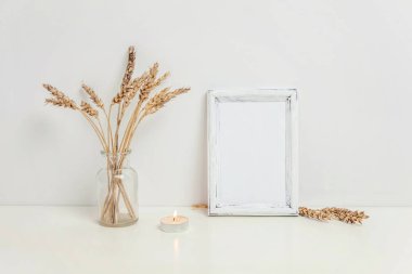 Dikey çerçeve mockup vahşi çavdar kokulu beyaz duvarının yakınında cam vazoda. Boş çerçeve tanıtım tasarım için sahte. Modern sanat için şablon çerçeveleme. Hygge İskandinav tarzı doğal Eko ev dekorasyonu