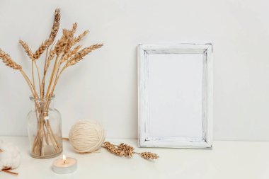 Dikey çerçeve mockup vahşi çavdar kokulu beyaz duvarının yakınında cam vazoda. Boş çerçeve tanıtım tasarım için sahte. Modern sanat için şablon çerçeveleme. Hygge İskandinav tarzı doğal Eko ev dekorasyonu