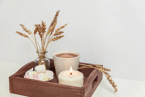 Natural eco home decor with cup coffee marshmallow candle on wooden tray. Early morning breakfast lifestyle background. Interior decoration with hot drink mug. Hygge scandinavian style copy space