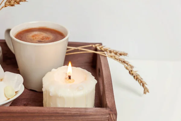 Natural eco home decor with cup coffee marshmallow candle on wooden tray. Early morning breakfast lifestyle background. Interior decoration with hot drink mug. Hygge scandinavian style copy space
