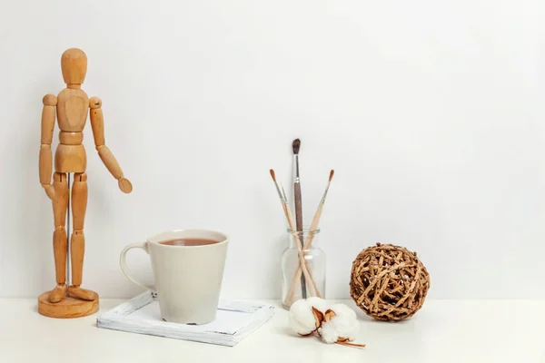 Home or office decor with mannequin coffee cup near white wall. Minimalism interior workplace artist supplies decoration background. Hygge scandinavian style workspace concept. Copy space mock up