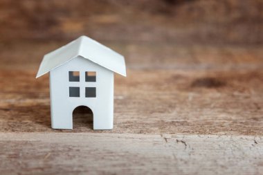 Miniature white toy model house in wooden background. Eco Village, abstract environmental background. Real estate mortgage property insurance dream home ecology concept clipart