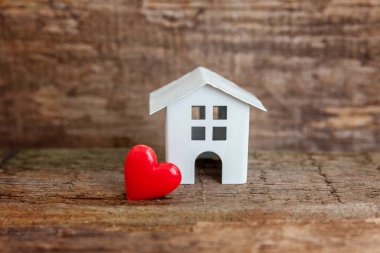 Minyatür beyaz oyuncak house ile ahşap bir masa üzerinde kırmızı kalp. Mortgage Emlak sigorta rüya ev concept