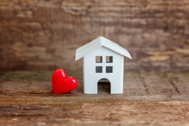 Minyatür beyaz oyuncak house ile ahşap bir masa üzerinde kırmızı kalp. Mortgage Emlak sigorta rüya ev concept