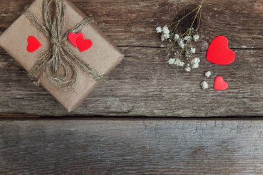 Hediye kutusu mevcut kaydırılan Kraft kağıt rustik trendy eski vintage ahşap zemin üzerine kırmızı kalp. 