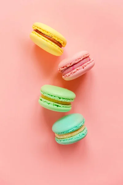 stock image Sweet almond colorful pink blue yellow green macarons or macaroon dessert cake isolated on trendy pink pastel background. 