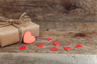 Hediye kutusu mevcut kaydırılan Kraft kağıt rustik trendy eski vintage ahşap zemin üzerine kırmızı kalp. 