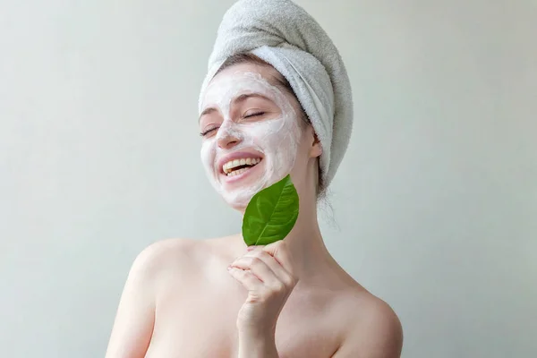 美白マスク または顔と分離した白い背景の上の手で緑の葉にクリームの栄養を頭の上のタオルで笑顔ブルネットの女性の肖像画 スキンケア クレンジング エコ有機化粧品スパ リラックス コンセプト — ストック写真
