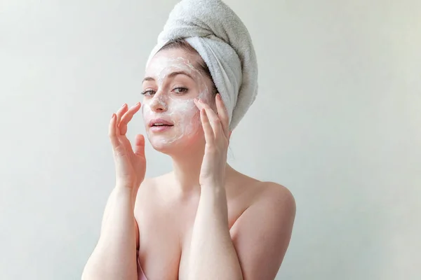 一个微笑的黑发妇女的美丽的画像在毛巾在头上使用白色营养的面具或奶油在面孔在白色背景隔绝 护肤性清洁水疗放松的概念 — 图库照片