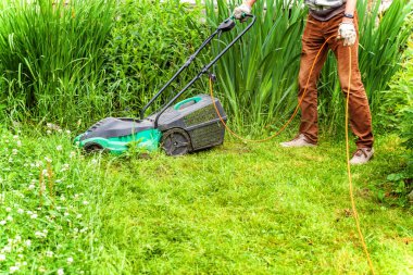 Adam arka bahçede çim biçme makinesi ile yeşil çim kesme