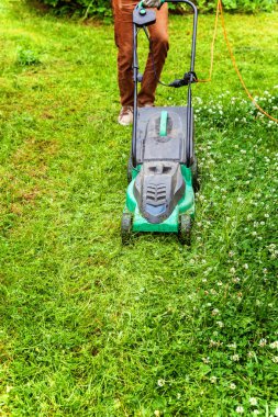 Adam arka bahçede çim biçme makinesi ile yeşil çim kesme