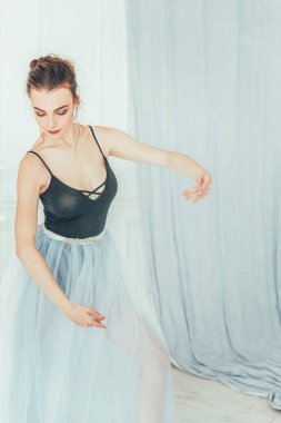Genç Klasik Bale dansçısı kadın dans dersi. Güzel zarif balerin pratik bale pozisyonlar yakınındaki beyaz ışık salonda büyük ayna mavi tutu etekle