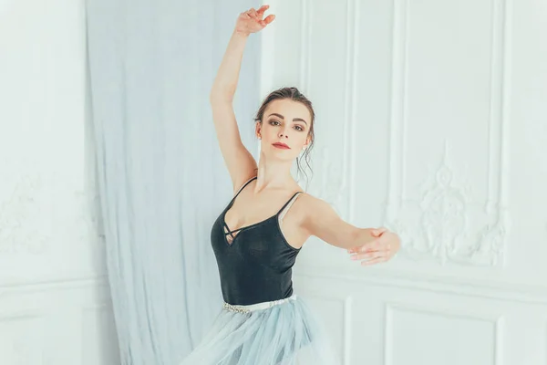 舞蹈课上年轻的古典芭蕾舞演员 美丽优雅的芭蕾舞演员练习芭蕾位置在蓝色 Tutu 裙子附近大镜子在白色光大厅 — 图库照片