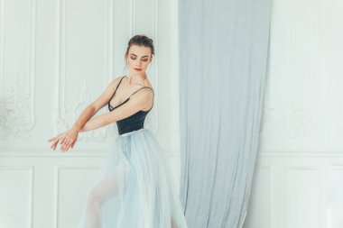 Genç Klasik Bale dansçısı kadın dans dersi. Güzel zarif balerin pratik bale pozisyonlar yakınındaki beyaz ışık salonda büyük ayna mavi tutu etekle