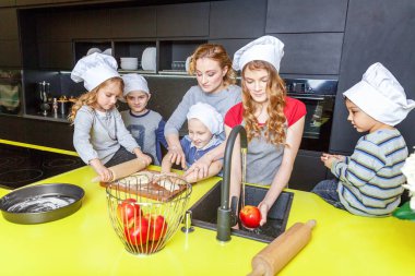 Mutlu aile mutfak. Anne ve beş çocuk hamur, fırında elmalı turta hazırlanıyor. Anne, kızı ve oğlu evde sağlıklı yemek pişirme ve eğleniyor. Yardım, ev içi, ekip çalışması annelik kavramı