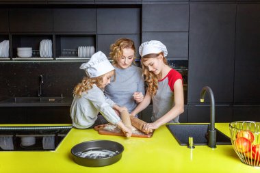 Mutlu aile mutfak. Anne ve iki çocuğu hamur, fırında elmalı turta hazırlanıyor. Anne ve kızı evde sağlıklı yemek pişirme ve eğleniyor. Yardım, ev içi, ekip çalışması annelik kavramı