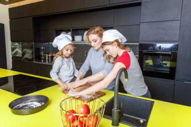 Mutlu aile mutfak. Anne ve iki çocuğu hamur, fırında elmalı turta hazırlanıyor. Anne ve kızı evde sağlıklı yemek pişirme ve eğleniyor. Yardım, ev içi, ekip çalışması annelik kavramı