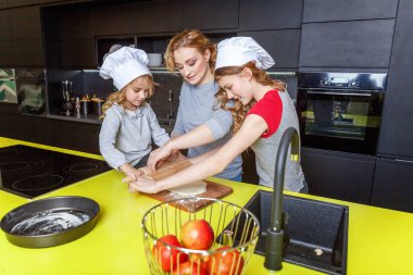 Mutlu aile mutfak. Anne ve iki çocuğu hamur, fırında elmalı turta hazırlanıyor. Anne ve kızı evde sağlıklı yemek pişirme ve eğleniyor. Yardım, ev içi, ekip çalışması annelik kavramı