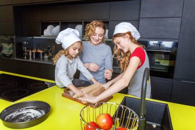 Mutlu aile mutfak. Anne ve iki çocuğu hamur, fırında elmalı turta hazırlanıyor. Anne ve kızı evde sağlıklı yemek pişirme ve eğleniyor. Yardım, ev içi, ekip çalışması annelik kavramı