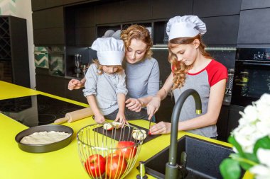 Mutlu aile mutfak. Anne ve iki çocuğu hamur, fırında elmalı turta hazırlanıyor. Anne ve kızı evde sağlıklı yemek pişirme ve eğleniyor. Ev, ekip çalışması yardımcı, annelik kavramı kadar yakın