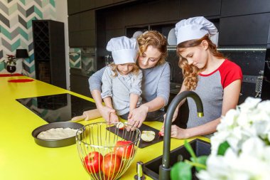 Mutlu aile mutfak. Anne ve iki çocuğu hamur, fırında elmalı turta hazırlanıyor. Anne ve kızı evde sağlıklı yemek pişirme ve eğleniyor. Yardım, ev içi, ekip çalışması annelik kavramı