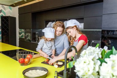 Mutlu aile mutfak. Anne ve iki çocuğu hamur, fırında elmalı turta hazırlanıyor. Anne ve kızı evde sağlıklı yemek pişirme ve eğleniyor. Yardım, ev içi, ekip çalışması annelik kavramı