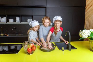 Mutlu aile mutfak. Anne ve iki çocuğu hamur, fırında elmalı turta hazırlanıyor. Anne ve kızı evde sağlıklı yemek pişirme ve eğleniyor. Yardım, ev içi, ekip çalışması annelik kavramı