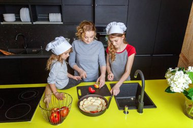 Mutlu aile mutfak. Anne ve iki çocuğu hamur, fırında elmalı turta hazırlanıyor. Anne ve kızı evde sağlıklı yemek pişirme ve eğleniyor. Yardım, ev içi, ekip çalışması annelik kavramı