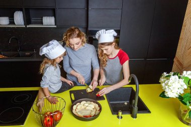 Mutlu aile mutfak. Anne ve iki çocuğu hamur, fırında elmalı turta hazırlanıyor. Anne ve kızı evde sağlıklı yemek pişirme ve eğleniyor. Yardım, ev içi, ekip çalışması annelik kavramı