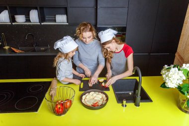 Mutlu aile mutfak. Anne ve iki çocuğu hamur, fırında elmalı turta hazırlanıyor. Anne ve kızı evde sağlıklı yemek pişirme ve eğleniyor. Yardım, ev içi, ekip çalışması annelik kavramı