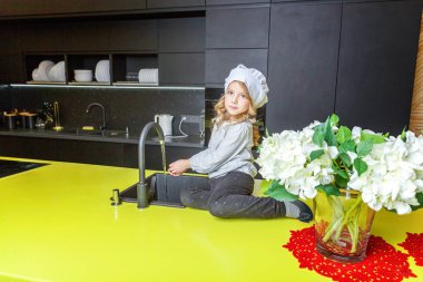 Küçük kız mutfakta gülümseyen yemek öğrenme Şef şapkalı. Çocuk evde sağlıklı yemek hazırlama ve eğleniyor. Çocukluk, gıda, sağlıklı beslenme, ev, ekip çalışması, yardım, Aile kavramı