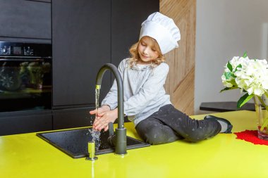 Küçük kız mutfakta gülümseyen yemek öğrenme Şef şapkalı. Çocuk evde sağlıklı yemek hazırlama ve eğleniyor. Çocukluk, gıda, sağlıklı beslenme, ev, ekip çalışması, yardım, Aile kavramı