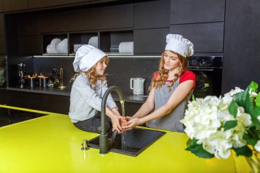 Şef ile iki kız bir sarılma ve mutfakta eğlenerek şapka. Kız küçük çocuk ve Genç kız evde sağlıklı yemek yemek. Çocukluk, Aile, ev, ekip çalışması kavramı yardım