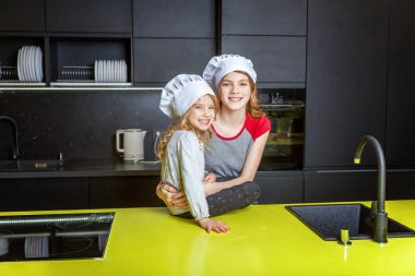 Şef ile iki kız bir sarılma ve mutfakta eğlenerek şapka. Kız küçük çocuk ve Genç kız evde sağlıklı yemek yemek. Çocukluk, Aile, ev, ekip çalışması kavramı yardım