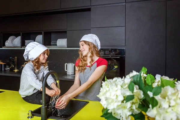 Şef ile iki kız bir sarılma ve mutfakta eğlenerek şapka. Kız küçük çocuk ve Genç kız evde sağlıklı yemek yemek. Çocukluk, Aile, ev, ekip çalışması kavramı yardım