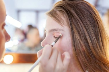 Makyaj ana uygulanan göz farı küçük güzel kız modeli için el. Profesyonel olun sanatçı tarafından uygulanıyor. Kalıcı makyaj ayrıntılı işlem olarak. Tarzı çocuk güzellik salonu photosession kavramı